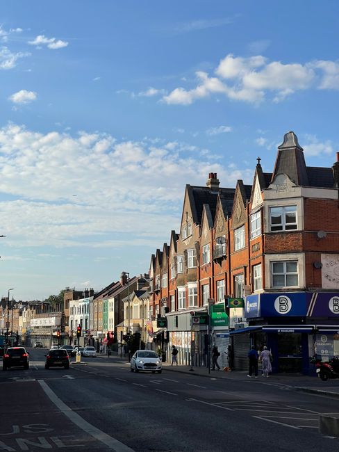 The image shows a street scene in Whitechapel with a row of multi-story Victorian-style terraced houses featuring brick facades, gabled roofs, and bay windows lining the right side of the road. The sk