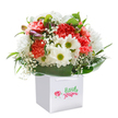 There's an airy delight woven through this Whitechapel bouquet, as if it has captured the mood of a sunlit walk past hidden gardens off Vallance Road. Nestled within a clean white gift bag, the arrangement pulses with energy-coral, peach, and radiant red carnations create playful texture, their petals lush and softly ruffled. Bright white daisies with golden-lime centres smile out from the medley, signaling happiness and an easy, open-hearted spirit. Threads of delicate white gypsophila give the bouquet a cloudlike, ethereal presence, prompting thoughts of fresh starts and gentle celebrations. Glimpses of unopened purple-tinged buds add intrigue, suggesting ongoing growth and anticipation. Embracing it all, deep, glossy green leaves arc in protective curves, their sheen reflecting expert craftsmanship and care typical along local Whitechapel flower stalls. With a full, rounded form and poised presentation, this bouquet sparkles against a pure white background-calling to mind both vibrancy and simplicity. Ready for delivery across Whitechapel or for celebrating moments big and small, it brings a little piece of East London's cheerful character wherever it goes, making it a thoughtful choice for birthdays, milestones, or simply to say you care.