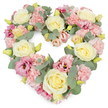 A pastel heart-shaped floral wreath appears against a bright white background, its densely packed flowers forming a gentle but unmistakable symbol of love and remembrance. Creamy ivory and soft yellow roses bloom throughout the design, each one rounded and velvety, the petals spiralling inward to give a sense of calm, enduring affection. Settled closely around them are clusters of ruffled pale pink carnations, their finely fringed petals overlapping to create a soft, cushion-like texture that makes the heart feel warm and embracing. Threaded through these softer tones, deeper magenta-pink and mauve lisianthus blooms introduce richer colour and an airy, more open petal shape, adding depth and subtle drama, like a quiet echo of emotion. Delicate sprigs of eucalyptus run through the arrangement, their circular, silvery-green leaves offering a cool contrast and helping to define the heart's smooth curves. Tiny yellowish-green buds are scattered here and there, suggesting renewal and hope even in sorrow. The flowers are arranged so closely that no gaps show, giving the wreath a full, luxurious appearance. In Whitechapel, this type of heart tribute might be chosen for a funeral, memorial service, or condolence gift delivered to a family near Whitechapel High Street or Stepney Green, a floral gesture that conveys sympathy without overwhelming the senses. It feels like something thoughtfully prepared by Whitechapel Florist, drawing on local experience of supporting families through loss and creating arrangements that reflect both cultural sensitivity and heartfelt care.